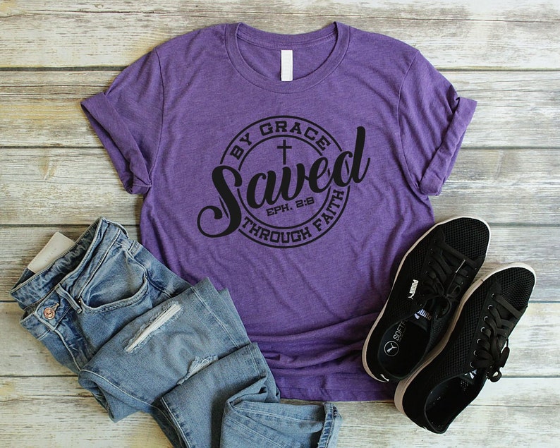 May include: Purple t-shirt with a black circle graphic that says "Saved by Grace through Faith" with a cross and the scripture reference "Eph. 2:8".