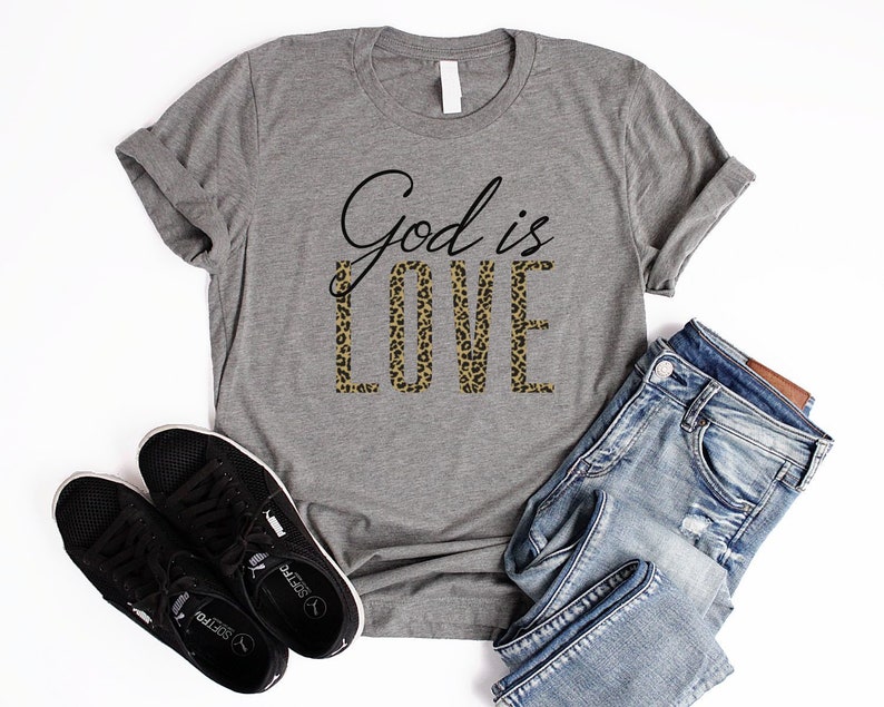 May include: A gray t-shirt with the text "God is Love" printed on it. The word "Love" is in a leopard print pattern.