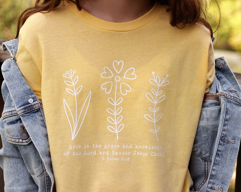 May include: Yellow t-shirt with a white floral design and the text "grow in the grace and knowledge of our Lord and Savior Jesus Christ 2 Peter 3:18"
