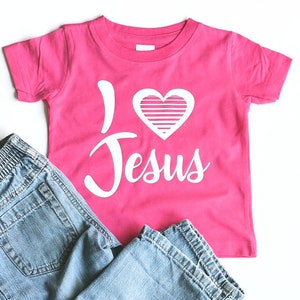 May include: Pink t-shirt with a white heart and the words "I love Jesus" printed on it.
