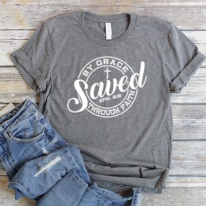 May include: Gray t-shirt with a white circle graphic that says "Saved by Grace through Faith Eph. 2:8" with a cross inside the circle.