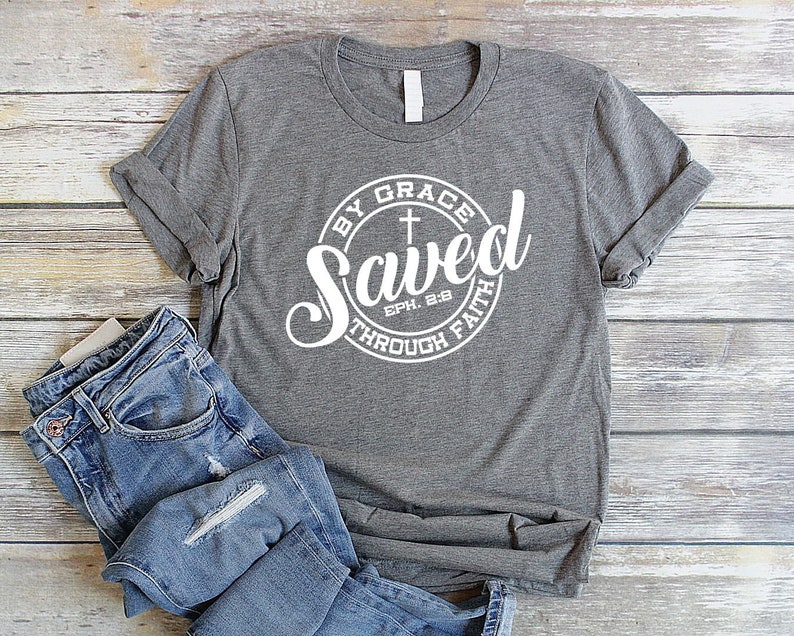 May include: Gray t-shirt with a white circle graphic that says "Saved by Grace through Faith Eph. 2:8" with a cross inside the circle.