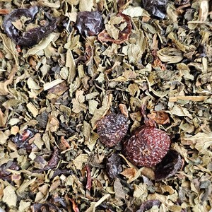 May include: Close-up of a blend of dried herbs and berries, including green leaves, dark brown berries, and red berries.