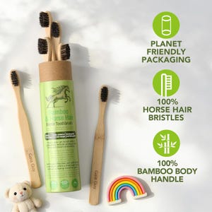 May include: A collection of bamboo toothbrushes with black bristles, displayed with a green and brown tube labeled "Bamboo & Horse Hair Bristle Toothbrush." The image also includes a rainbow-shaped decoration and text that reads "Planet Friendly Packaging."