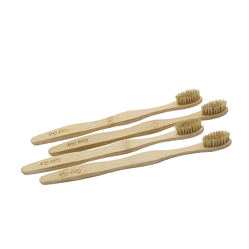 May include: Four natural bamboo toothbrushes with brown bristles. Each toothbrush has the text "Gaia Guy" printed on the handle.