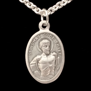 Może przedstawiać: Srebrny naszyjnik z zawieszką w postaci religijnego medalu z wizerunkiem Świętego Dismasza, Dobrego Łotra, na srebrnym łańcuszku.