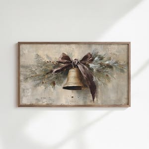 Könnte beinhalten: Gerahmtes Gemälde einer goldenen Glocke mit braunem Band und Grünzeug. Die Glocke ist mittig platziert, das Band ist darüber zu einer Schleife gebunden. Der Hintergrund ist ein gedämpftes, strukturiertes Beige.