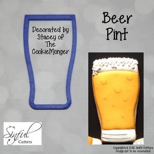 May include: A blue plastic cookie cutter in the shape of a beer pint glass next to a decorated cookie. The cookie is yellow with white foam and a white base. Text on the image says "Beer Pint".