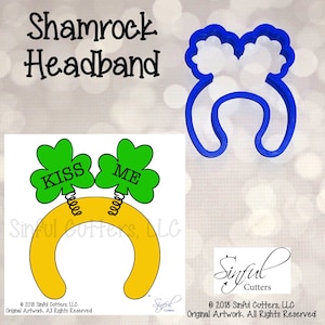 May include: A yellow headband with two green shamrock cutouts. The shamrocks have the words "KISS" and "ME" written on them. The headband is a cookie cutter.