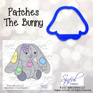 May include: A gray bunny cookie cutter with a patchwork design. The bunny is sitting with its ears up and has a flower on its head. The cutter is labeled "Patches the Bunny".