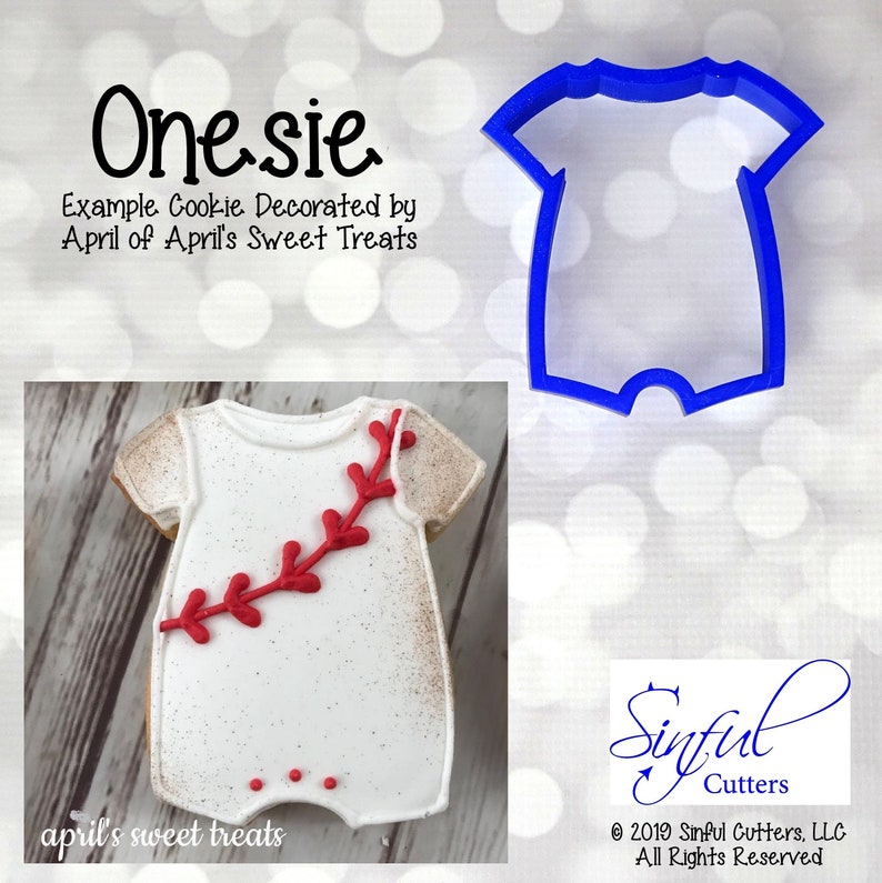 May include: A blue plastic cookie cutter shaped like a onesie. The onesie has a short-sleeve design and a snap closure at the bottom. The cookie cutter is on a white background with a blurred bokeh effect.