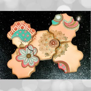 Puede incluir: Una variedad de galletas decoradas con intrincados detalles. Cada galleta presenta un diseño único con colores pastel, incluyendo rosa, turquesa y dorado. Las galletas están dispuestas en un patrón decorativo, mostrando patrones florales y paisley detallados.