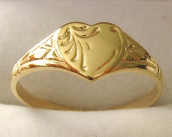 Puede incluir: Un anillo de sello de oro en forma de corazón con un diseño intrincado en la banda.