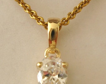 May include: A gold chain necklace with a pendant featuring a clear oval-shaped gemstone.
