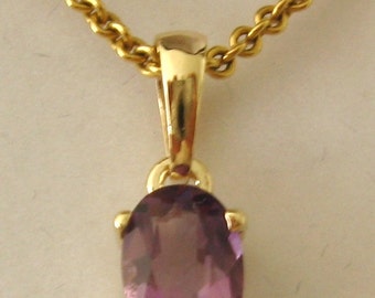May include: A gold chain necklace with a pendant featuring a purple oval gemstone.