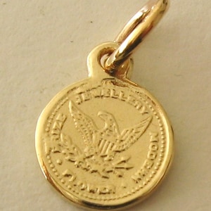 May include: Gold-toned charm featuring an eagle with outstretched wings and the words "The United States of America" around the edge.