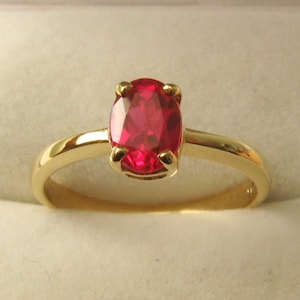 May include: A gold ring with a red oval gemstone.