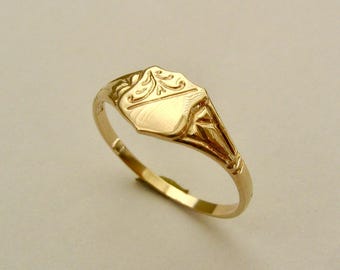 May include: A gold signet ring with an engraved design on the top. The ring is a classic style and would make a great gift.