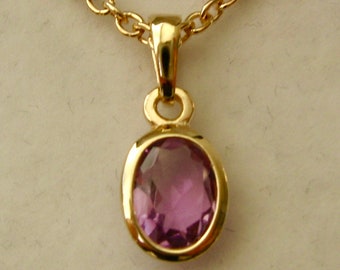 May include: A gold chain necklace with a pendant featuring a light purple oval gemstone.