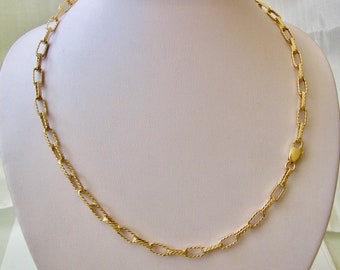 May include: A gold chain necklace with a delicate, twisted link design. The chain is made of small, rectangular links that are connected together to create a continuous loop.
