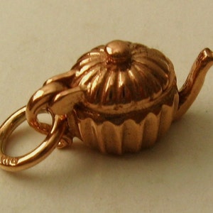 May include: A gold-tone teapot charm with a detailed design. The charm has a loop for attaching to a bracelet or necklace.