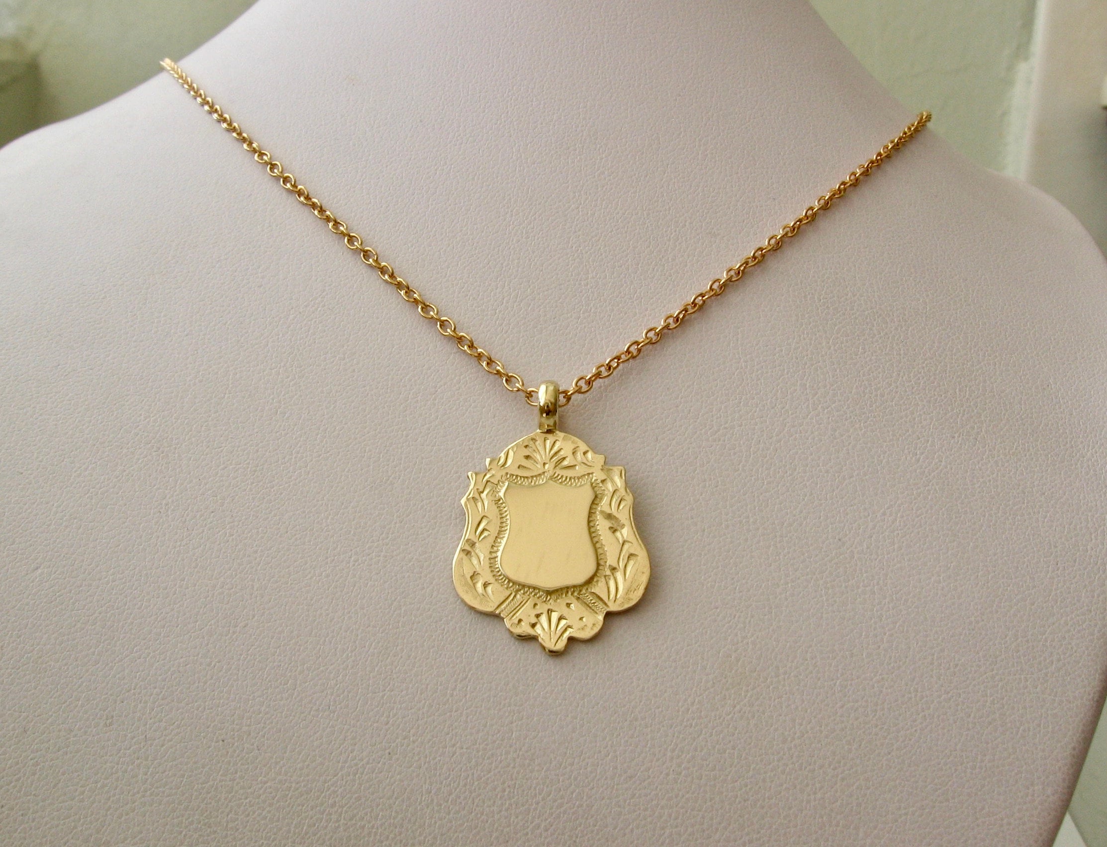 Gold shield best sale pendant