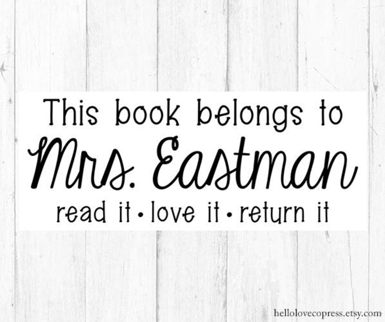 May include: Black and white text on a white wood background. The text reads "This book belongs to Mrs. Eastman read it. love it. return it."