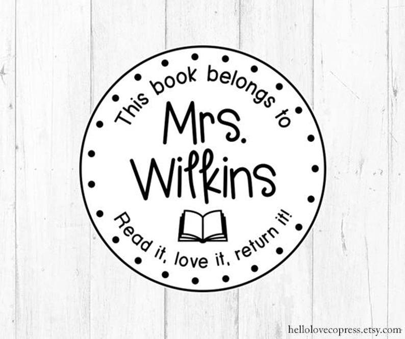 Puede incluir: Sello circular blanco y negro con el texto "This book belongs to Mrs. Wilkins Read it, love it, return it!" y una imagen de un libro abierto.