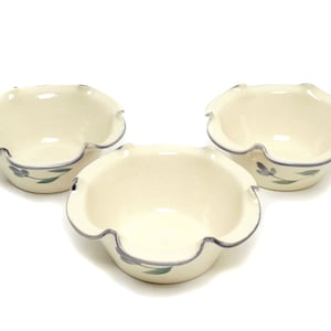 May include: Three white ceramic bowls with scalloped edges and blue and green floral designs.