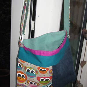 May include: A teal, pink and blue fabric tote bag with a monkey face pattern. The bag has a long strap and a zip closure.