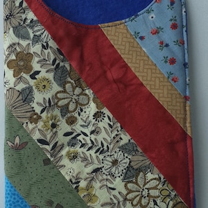 May include: A blue fabric pouch with a patchwork design. The pouch is made of different fabrics with floral patterns, geometric patterns, and solid colours. The pouch is approximately 10 cm wide and 15 cm tall.