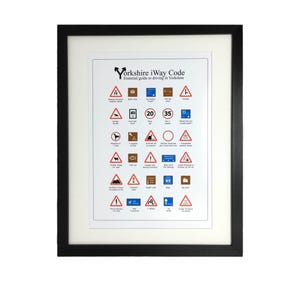May include: A white framed poster with the title "Yorkshire iWay Code: Essential guide to driving in Yorkshire". The poster features a collection of humorous road signs with Yorkshire-specific sayings and illustrations.