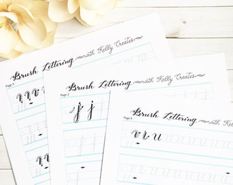 May include: Three pages of a brush lettering workbook with the title "Brush Lettering - with Kelly Creates" at the top of each page. The pages show the letters "m", "j", and "v, l, u" with practice lines.