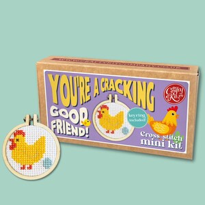 May include: A cross-stitch mini kit with a chicken design. The kit includes a wooden hoop with a yellow chicken cross-stitch pattern, a box with the text "You're a Cracking Good Friend!" and a keyring.