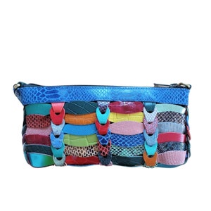 Op de afbeelding: Een kleine, blauwe, veelkleurige leren clutch met een ritssluiting. De clutch is gemaakt van verschillende gekleurde leren stukken die in een golfpatroon aan elkaar zijn genaaid.