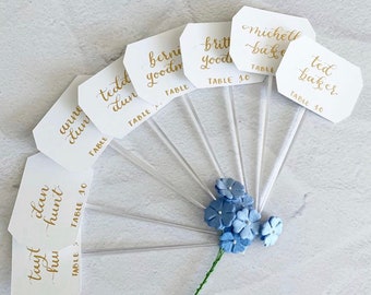 Calligraphy-Trimmed Cocktail Stirrers | White Banner Escort Cards | Champagne Flute Glass Place Cards | Sip & Be Seated Wedding Elegance.