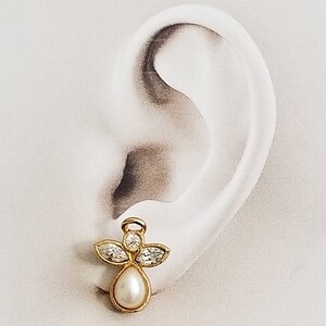 May include: Gold angel charm earring with clear crystal accents and a white pearl drop.