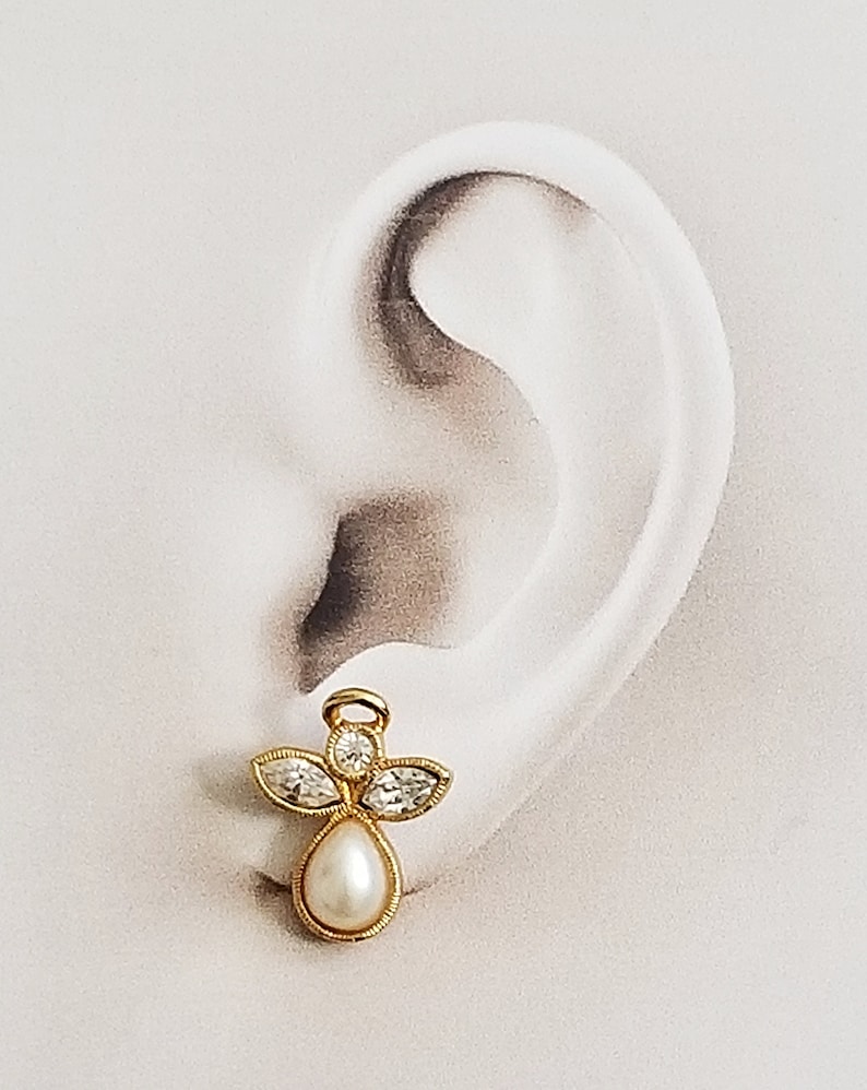 May include: Gold angel charm earring with clear crystal accents and a white pearl drop.