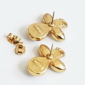 May include: A pair of gold-tone angel-shaped earrings with clear rhinestones. The earrings have a post back closure and are marked "CRYSTAL" on the back.