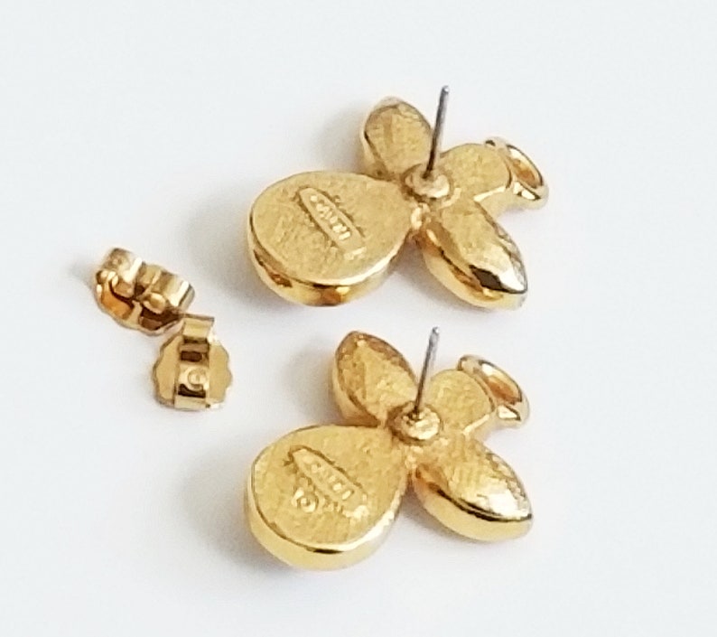 May include: A pair of gold-tone angel-shaped earrings with clear rhinestones. The earrings have a post back closure and are marked "CRYSTAL" on the back.
