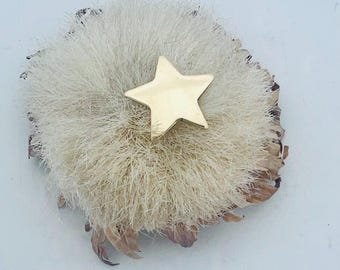 以下が含まれることがあります： 金色の星が特徴的な、ベージュと茶色のテクスチャード加工の花柄デザインが施された、ユニークな手作りのブローチ。 このブローチは、自然でオーガニックな美しさがあり、どんな服装にも気まぐれな雰囲気を添えるのに最適です。