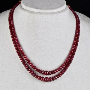 May include: A double strand necklace made of dark red ruby beads.