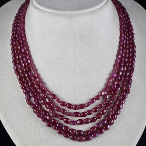 Könnte beinhalten: Eine mehrreihige Halskette aus ovalen, tief roten Rubinperlen.