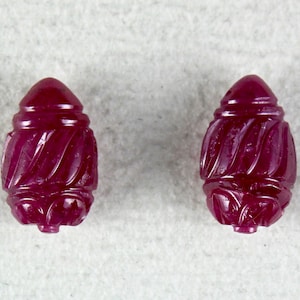 May include: Two carved ruby red gemstone beads with a swirl design.
