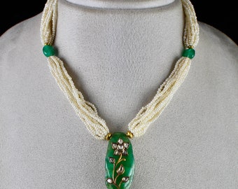 Puede incluir: Un collar de perlas de múltiples hilos con un colgante de piedra preciosa verde con un diseño de flor de oro y pequeños diamantes.