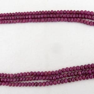 May include: A multi-strand necklace composed of small, round, deep red beads. The necklace has a woven closure at each end. The beads are strung together to create a layered effect, suitable for jewelry.