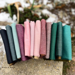Peut inclure: Un assortiment de 10 échantillons de tissu dans différentes nuances de rose, vert et bleu. Le tissu est doux, tissé et présente une texture subtile. Les échantillons sont disposés en rangée, la teinte la plus foncée à gauche et la plus claire à droite.