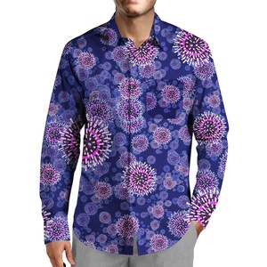 Könnte beinhalten: Ein langärmeliges Hemd in tiefem Blau mit einem sich wiederholenden Muster aus stilisierten, kugelförmigen Blumendesigns in Lila, Rosa und Weiß. Das Hemd hat einen klassischen Kragen und eine einzelne Brusttasche.