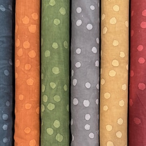 May include: Six fabric rolls with a white polka dot pattern on different colored backgrounds. The colors are blue, orange, green, gray, yellow, and red.