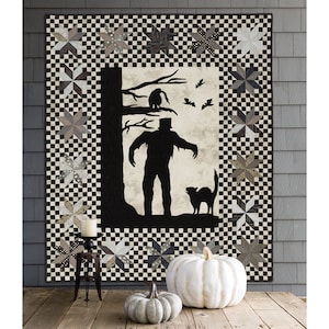 May include: A black and white quilt with a silhouette of a monster, a cat, and bats. The quilt is framed with a black and white checkered border and a black and white star pattern.